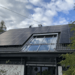 Solar panels installed and fitted on a roof with a skylight window.. - Solar Panel Installers UK