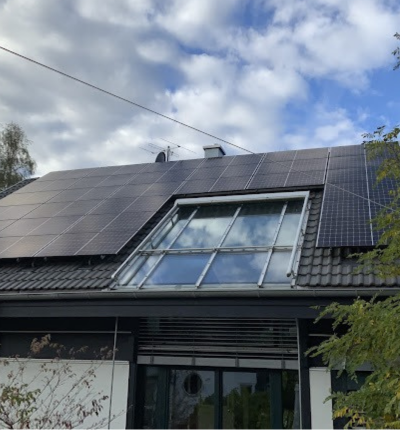 Solar panels installed and fitted on a roof with a skylight window.. - Solar Panel Installers UK
