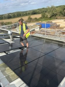 Installer on commercial roof with black solar panels