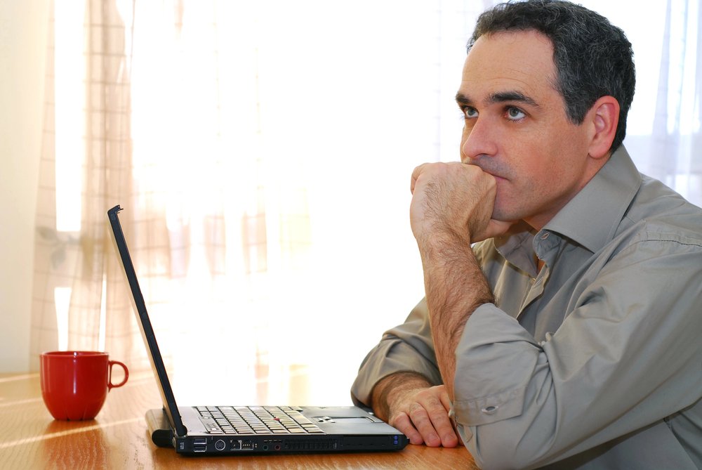 Man Sitting At A Desk And Looking Into His Computer