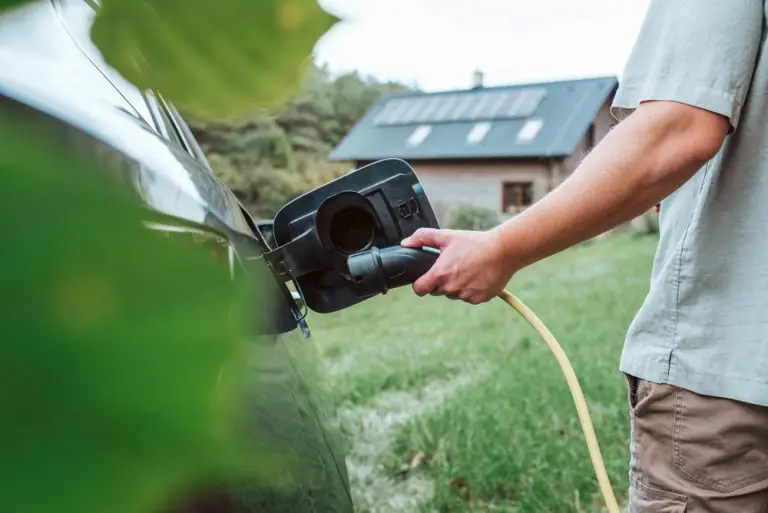 Close Up Of Man Charging Electric Car, Plugging Charger In Charging Port.